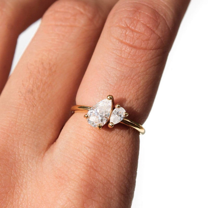 Anillo de oro amarillo 18k con dos diamantes de laboratorio corte pera de diferentes tamaños unidos en el centro.
