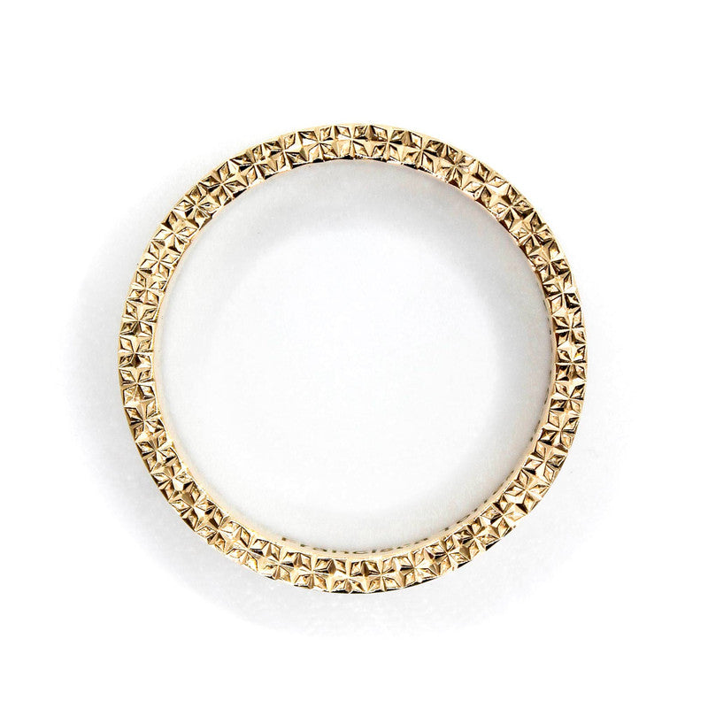 Argolla de matrimonio en oro amarillo 18k con grabado geométrico realizado a mano con buril y acabado brillante.