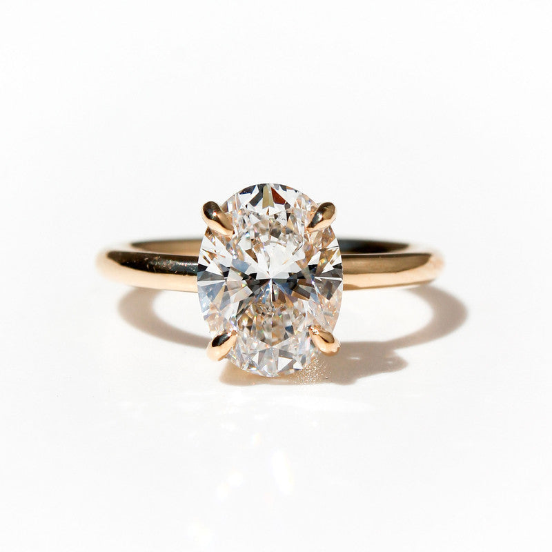 Anillo de oro amarillo con diamante ovalado brillante de gran tamaño sobre fondo blanco.