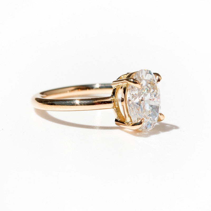 Anillo de oro amarillo con diamante ovalado brillante de gran tamaño sobre fondo blanco.