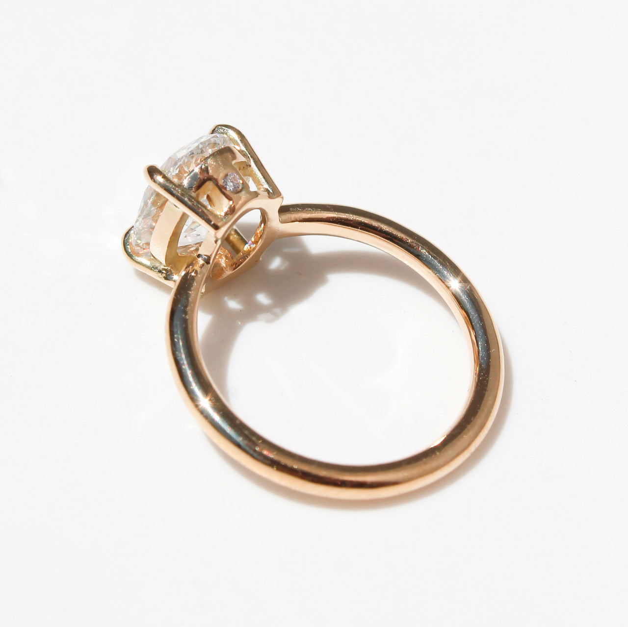 Anillo de oro amarillo con diamante ovalado brillante de gran tamaño sobre fondo blanco.