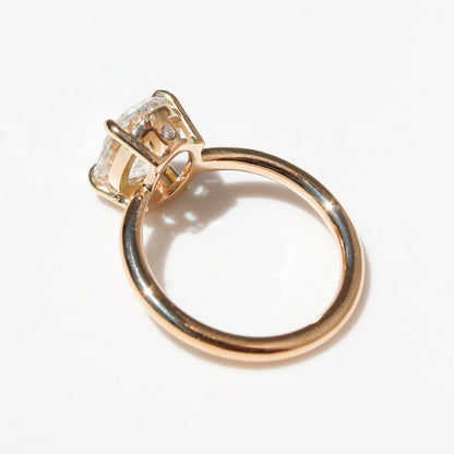 Anillo de oro amarillo con diamante ovalado brillante de gran tamaño sobre fondo blanco.