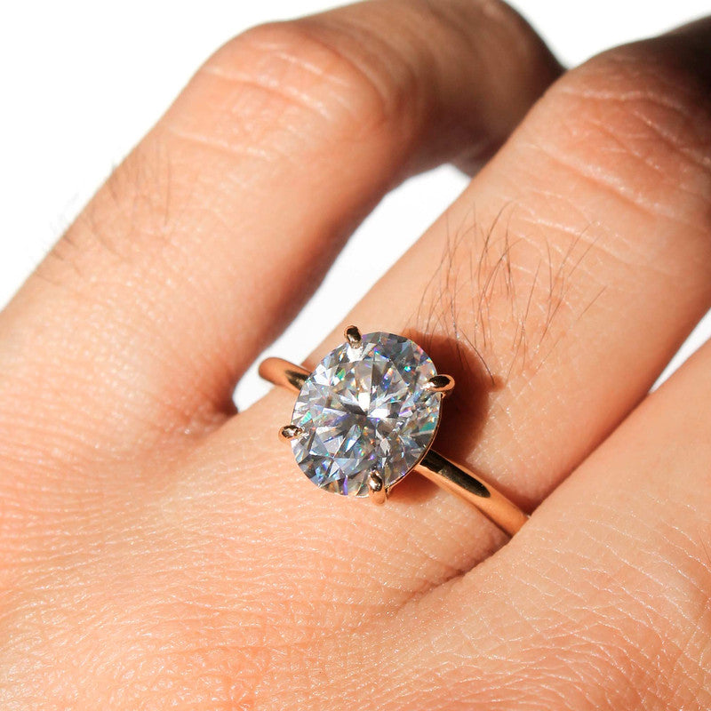 Anillo de oro amarillo con diamante ovalado brillante de gran tamaño sobre fondo blanco.